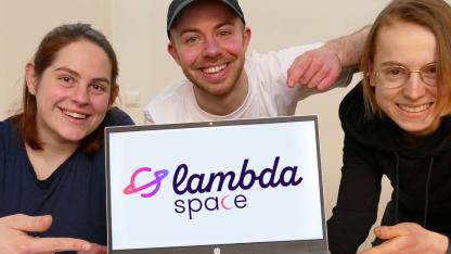 3 Personen mit einem Laptop, auf dem Bildschirm das Logo von lambda space